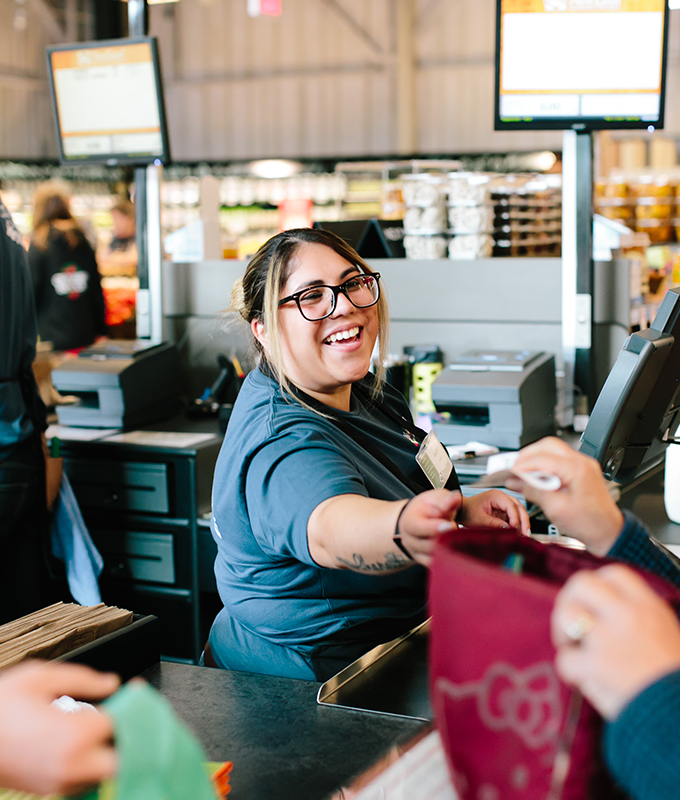 a new leaf employee smiling and holding a paper bag of groceries