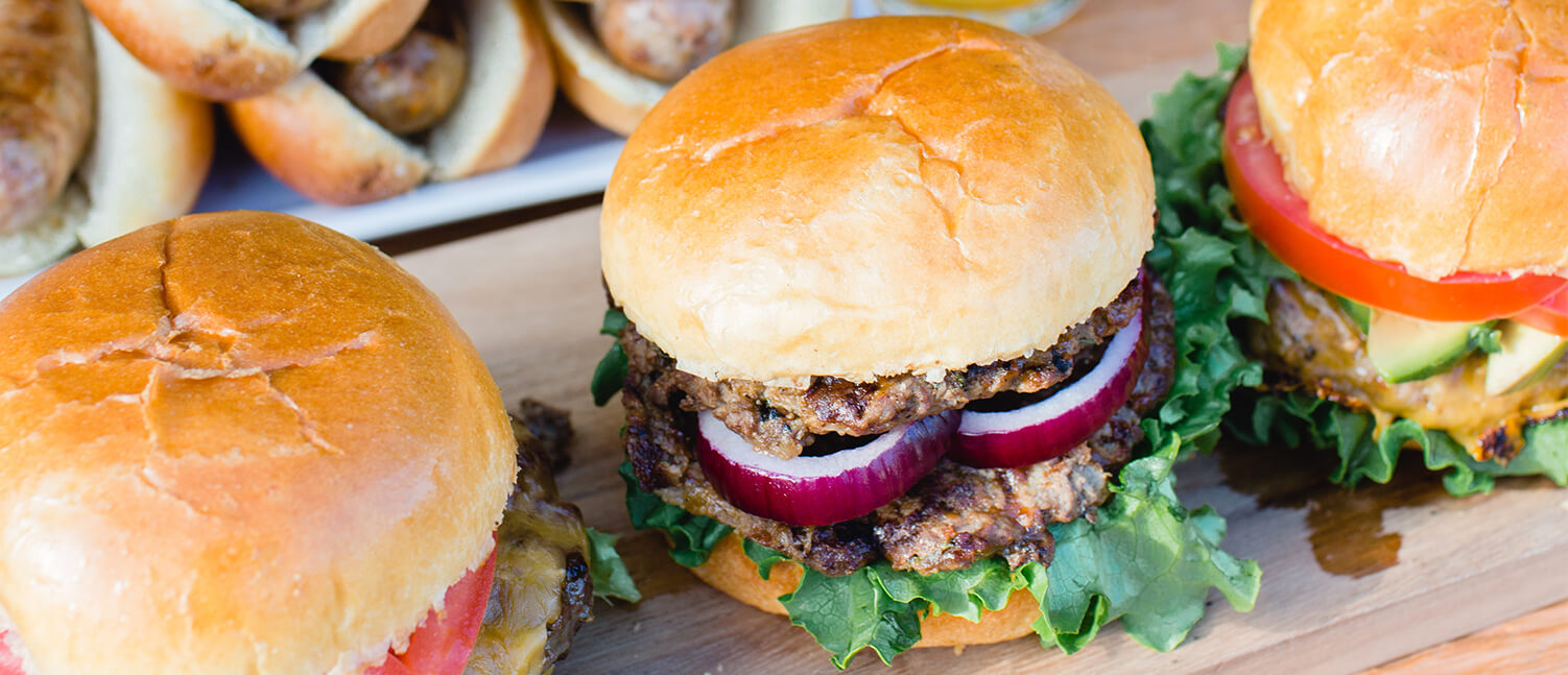 burgers on a platter with buns, onions and lettuce