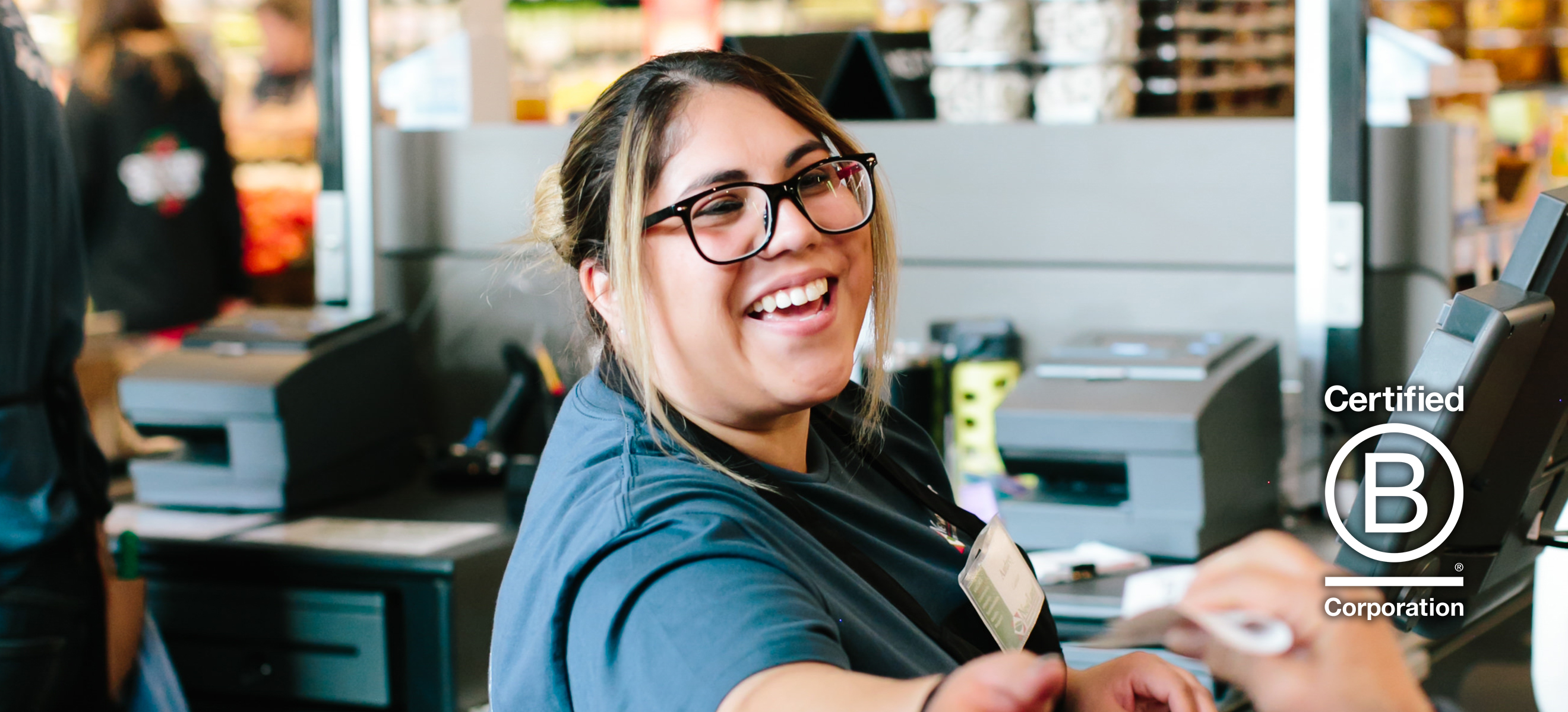 A smiling employee holding a reusable bag filled with produce